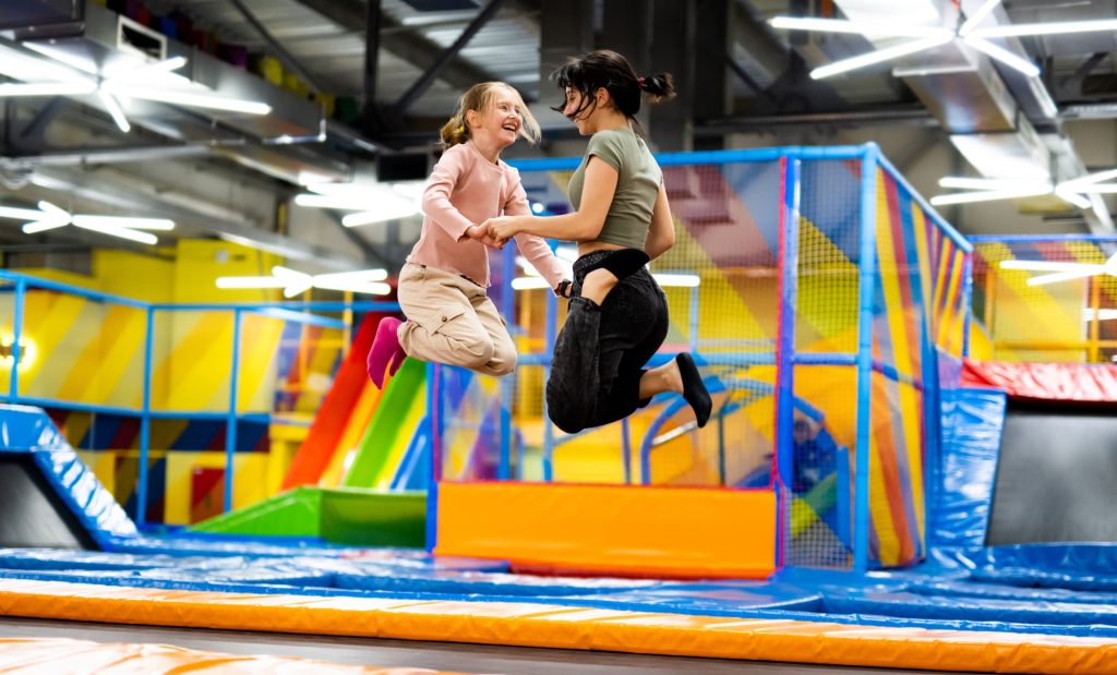 Girls jumping together on colorful trampoline at playground park